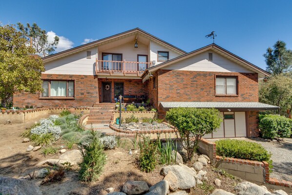 Stunning two-story residence with a symmetrical facade, featuring a balcony and a beautifully landscaped garden.