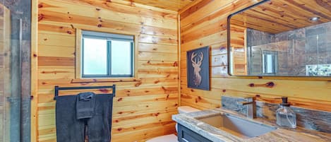A wooden-paneled bathroom with a toilet, sink, and a window.