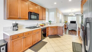 A modern kitchen with wooden cabinets, a stainless steel refrigerator, and a built-in microwave. - Spacious Bay Point Family Home w/ Private Yard! (Pittsburg)
