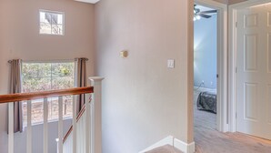 A staircase with a wooden handrail leading to a landing with a small window. - Spacious Bay Point Family Home w/ Private Yard! (Pittsburg)