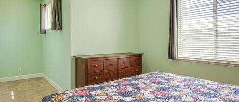 A bedroom with a bed, a dresser, a window with blinds, and a ceiling fan.