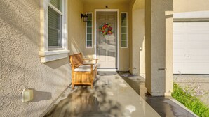 A house entrance with a bench, a door with a wreath, and a garage door. - Spacious Bay Point Family Home w/ Private Yard! (Pittsburg)
