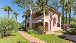 A two-story building with a balcony, a covered patio, and a pathway leading to the entrance. - Sophia near Porec big private Garden (Nova Vas)