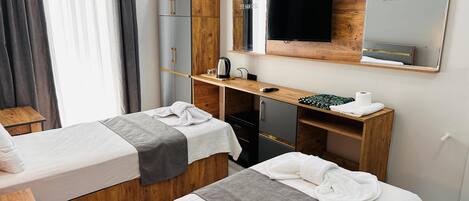 Una habitación de hotel con dos camas, televisión, escritorio de madera y espejo.