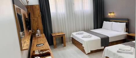 Una habitación de hotel con cama, mesitas de noche, escritorio, espejo y ventana con cortinas.