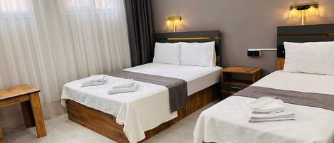 Habitación de hotel con dos camas, una mesita de noche de madera y una pequeña mesa.