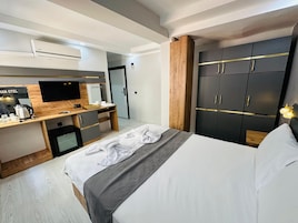 Una habitación de hotel con cama, escritorio con computadora, televisor y armario.