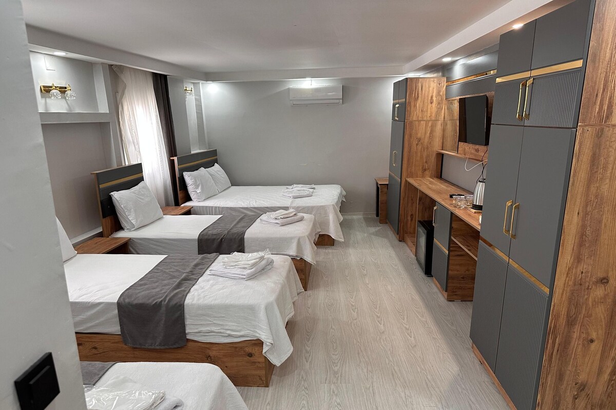 Una habitación de hotel con tres camas, un armario, un escritorio y un espejo.
