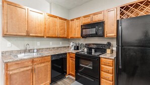 Una cocina con armarios de madera, un refrigerador negro, un microondas, una estufa y un lavavajillas.