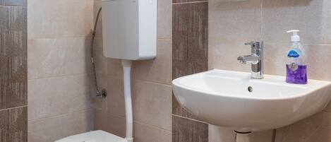 A bathroom with a toilet, sink, and mirror.