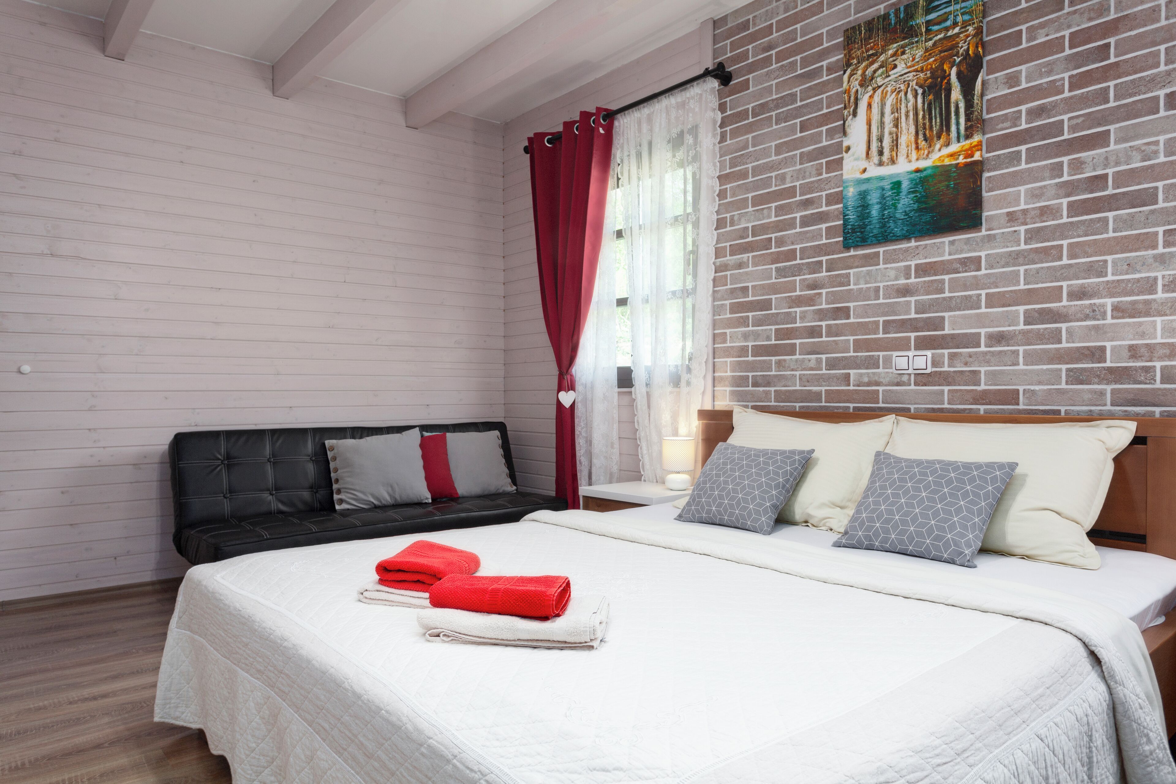 Een hotelkamer met een bed, een zwarte bank en een schilderij aan de muur.