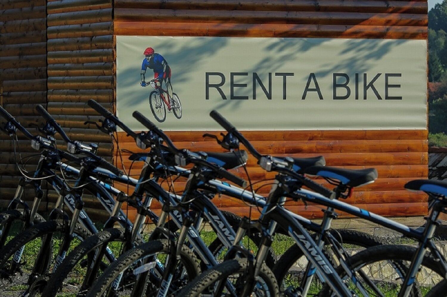 Una fila de bicicletas estacionadas frente a un edificio con un letrero que dice 'RENT A BIKE'.