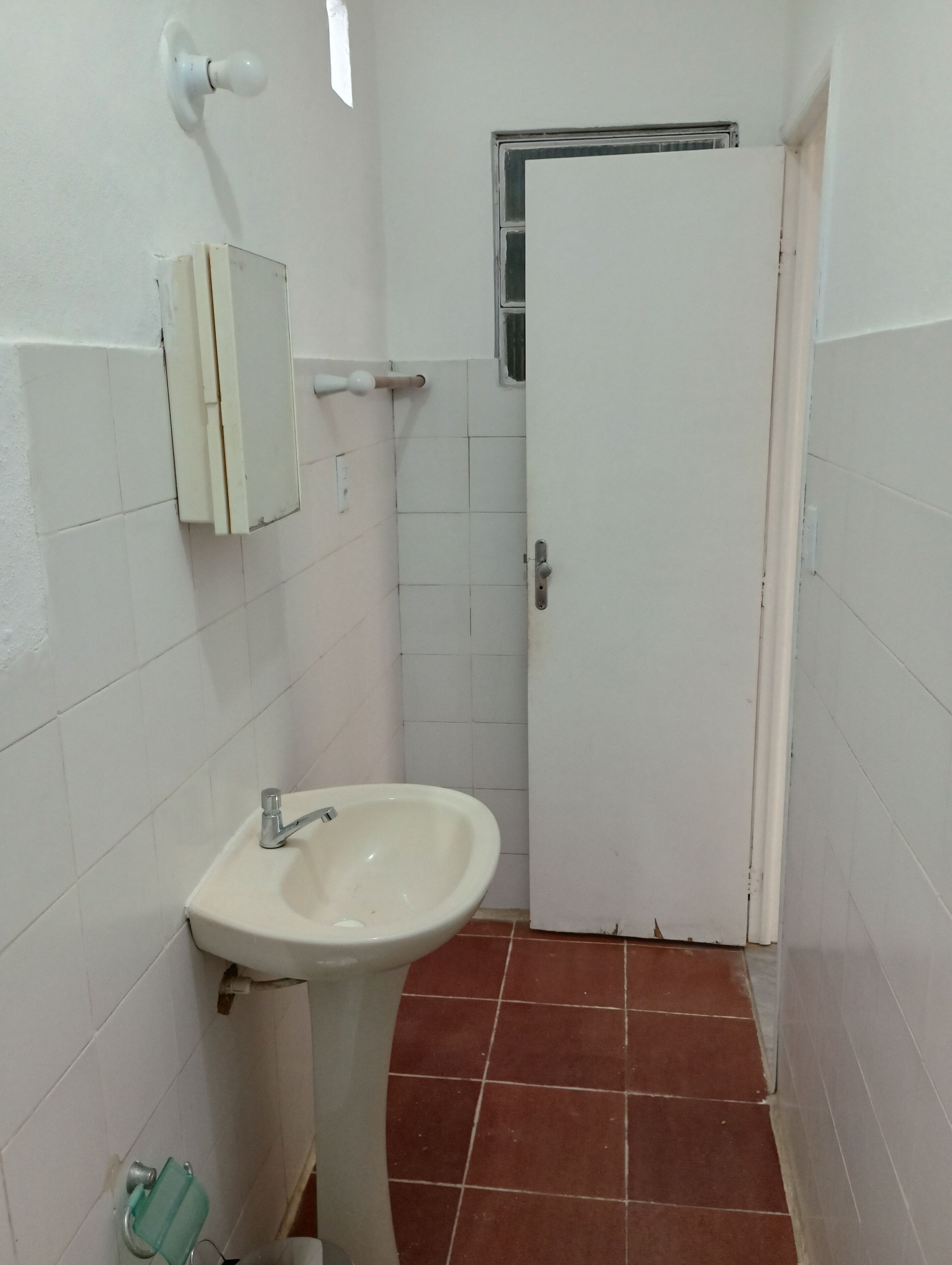 Un baño pequeño con un lavamanos blanco, un espejo y una puerta.
