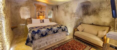 A room with a bed, a sofa, a rug, and a wall-mounted TV.