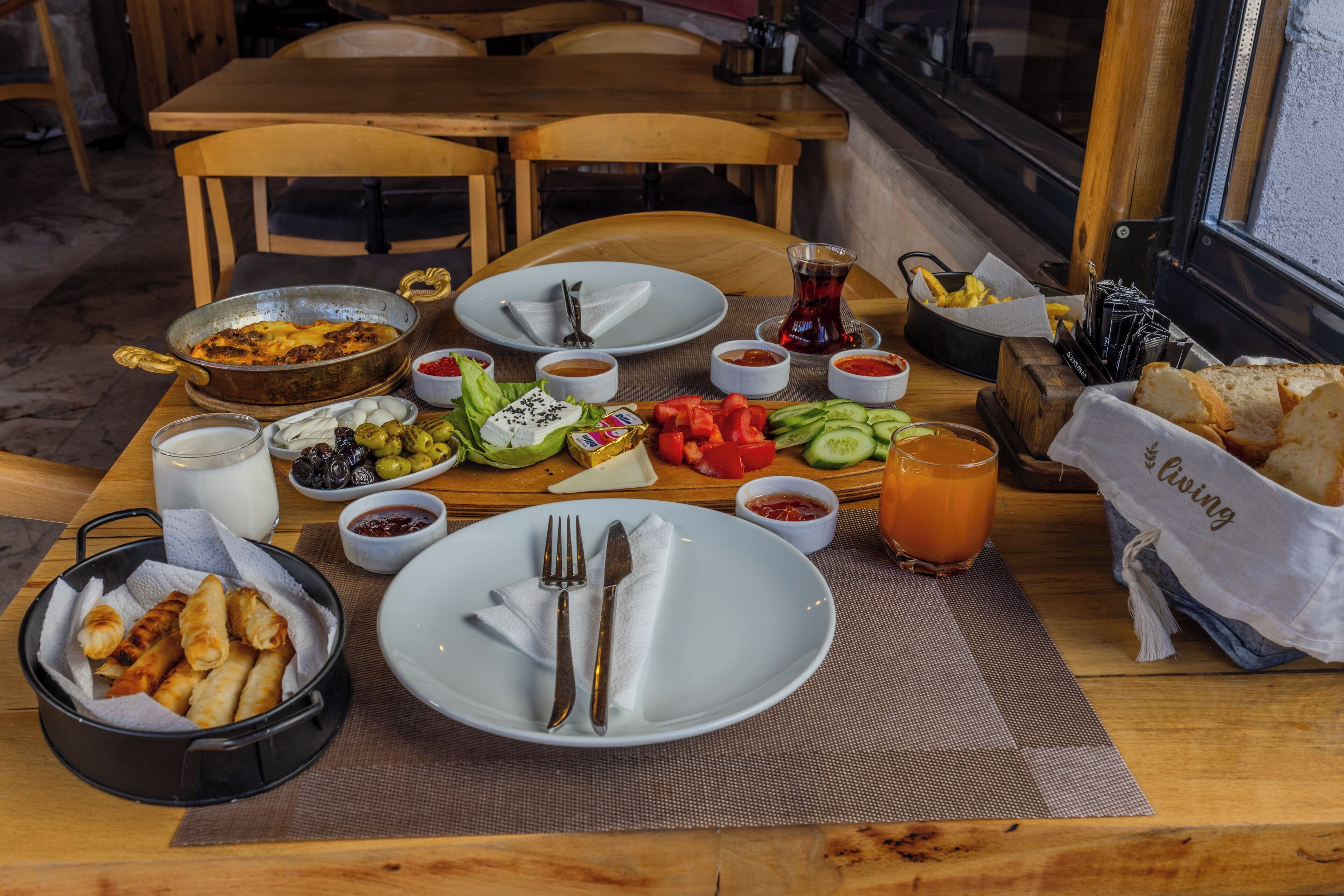 A dining table set with various dishes, including a pan of food, plates, utensils, and condiments.