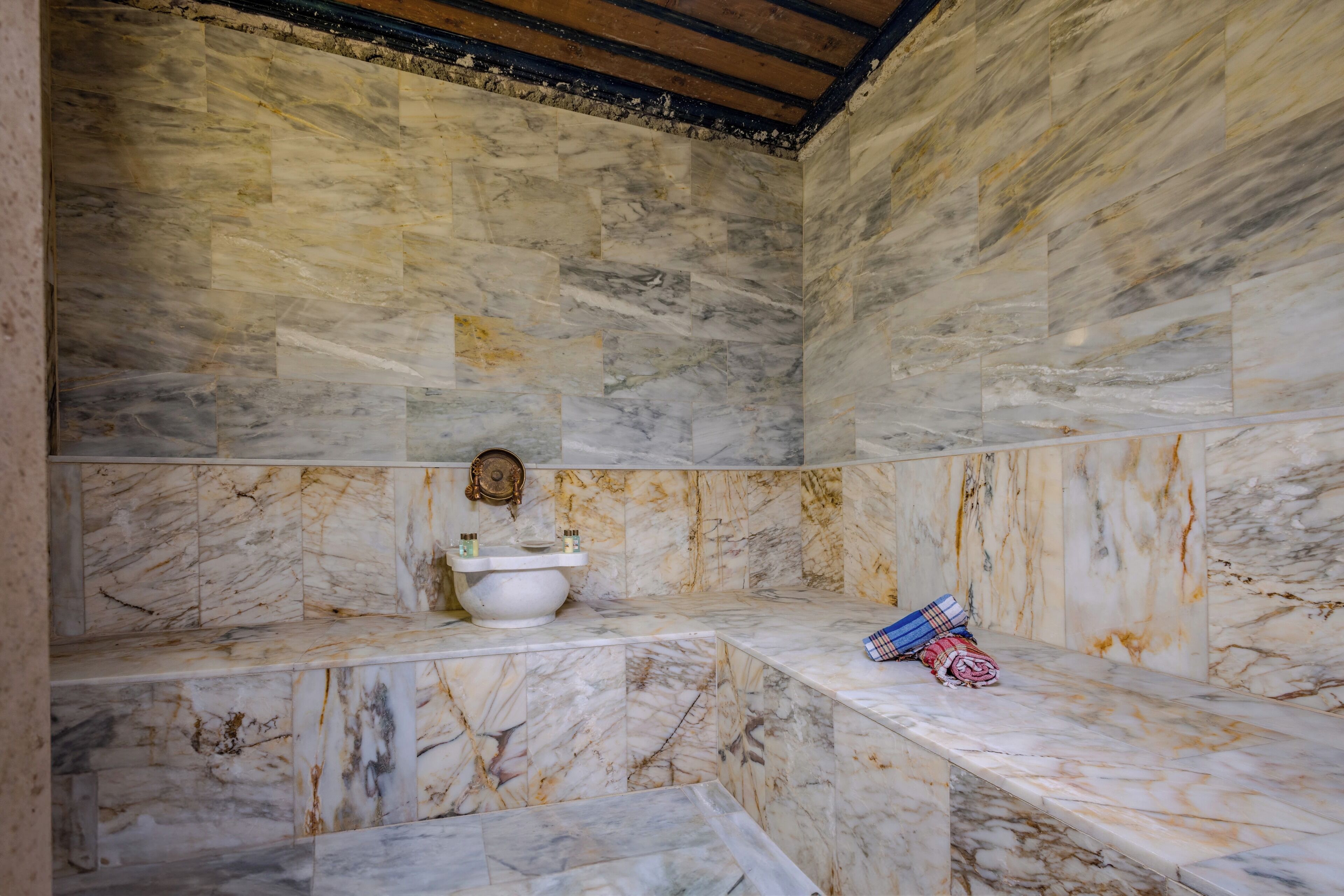 A bathroom with marble walls and a bench.