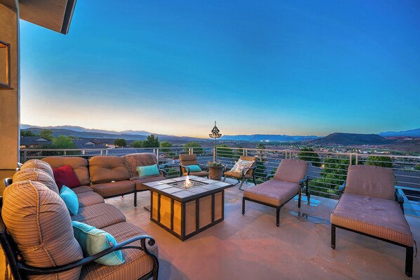 A rooftop terrace with outdoor seating, a fire feature, and a view of distant mountains.