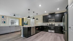 A modern kitchen with dark cabinets, stainless steel appliances, and pendant lighting. - Last Minute Disney! Private Pool, Hot Tub, Game Room & Themed Bedrooms. Book Now! #110895 (Orlando)