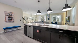 A modern kitchen with a central island, black cabinetry, and pendant lighting. - Last Minute Disney! Private Pool, Hot Tub, Game Room & Themed Bedrooms. Book Now! #110895 (Orlando)