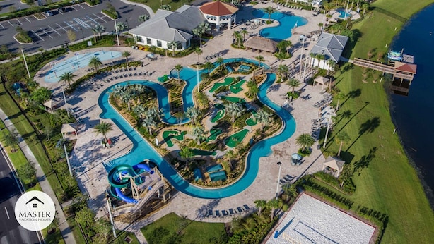 Ein Luftbild eines Resorts mit mehreren Swimmingpools, einem Strandbereich und einem großen Gebäude mit rotem Dach.