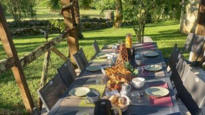 An outdoor dining area with a table set for four, surrounded by chairs, and a stone wall in the background. - Mas Laborde (Mauroux)
