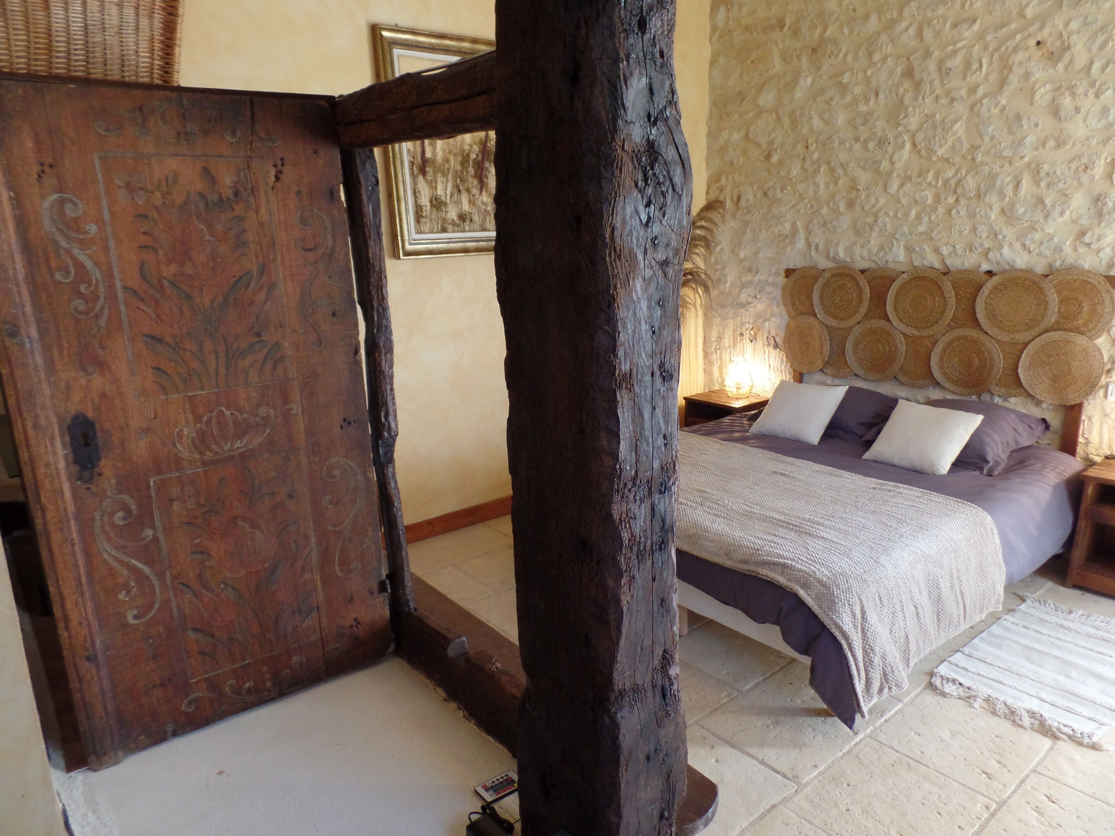 A bedroom with a wooden bed frame, a stone wall, and a woven headboard.