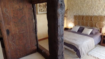 A bedroom with a wooden bed frame, a stone wall, and a woven headboard.
