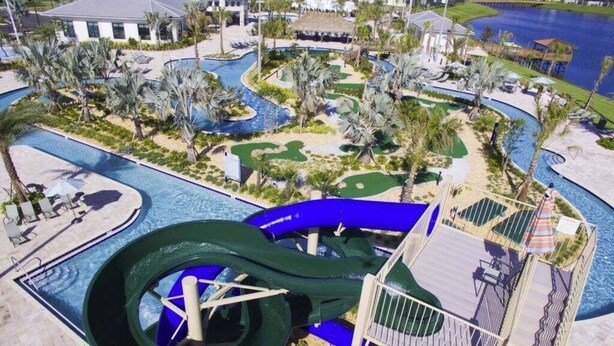 Parque aquático com um escorregador grande, palmeiras e área de piscina.