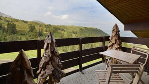 A wooden deck with a table and chairs overlooking a mountainous landscape. - 100m from resort center, 6th floor, view ski slopes, terrace, balcony, tv, ski locker, 57m² (La Plagne)