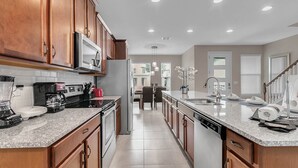 Une cuisine moderne avec des meubles en bois, des appareils en acier inoxydable et un plan de travail en granit.