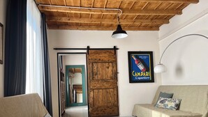 Une pièce avec un plafond en bois, un canapé, un divan, un miroir et une affiche accrochée au mur.