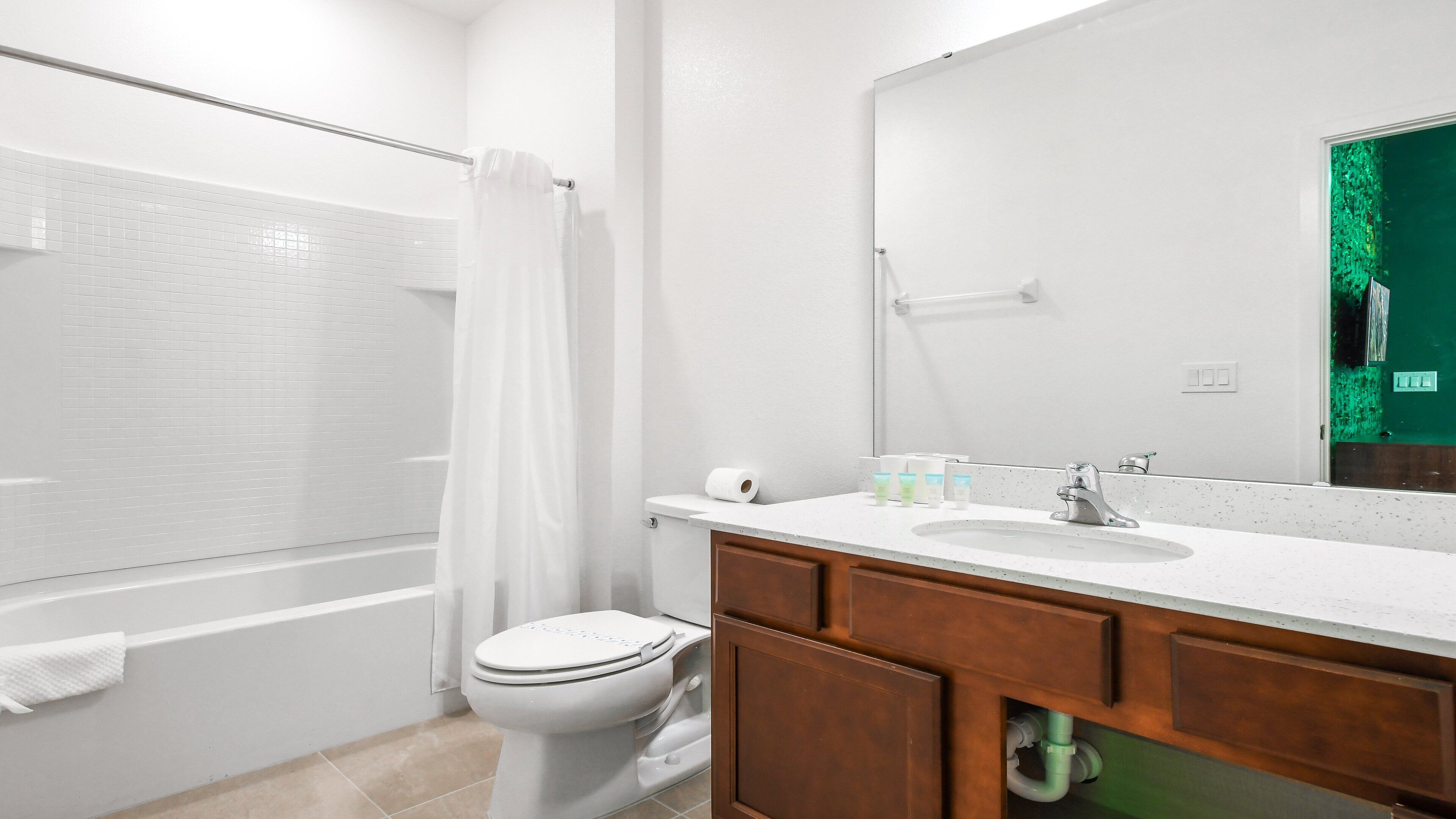 Ein modernes Badezimmer mit einer weißen Badewanne, einer Toilette, einem Waschbecken mit Spiegel und Holzschränken.