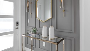 A modern interior with a glass console table, two white vases with gold accents, a hexagonal mirror, and two wall-mounted light fixtures. - Last Minute Disney Getaway! Private Pool & Themed Bedrooms. Book Now! #111841 (Orlando)