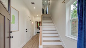 A staircase leading to a second floor, with a wooden floor and white walls. - Rooftop Movie Oasis: 3bd - Games - Patio (Houston)