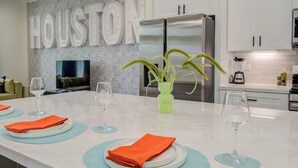 A modern kitchen with a marble countertop, stainless steel appliances, and a decorative wall with the word "HOUSTON". - Rooftop Movie Oasis: 3bd - Games - Patio (Houston)