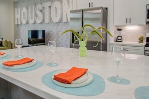 A modern kitchen with a marble countertop, stainless steel appliances, and a decorative wall with the word "HOUSTON".