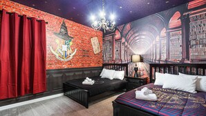 A room with a brick wall, a large Hogwarts crest, a black sofa, a bed with a colorful blanket, and a chandelier. - Last Minute Disney! Private Pool, Hot Tub, Game Room & Themed Bedrooms. Book Now! #112541 (Orlando)