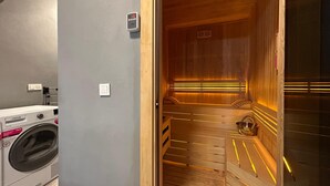 A sauna with wooden benches and a visible control panel.