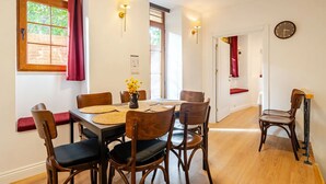 A dining area with a wooden table, chairs, and a vase of yellow flowers.