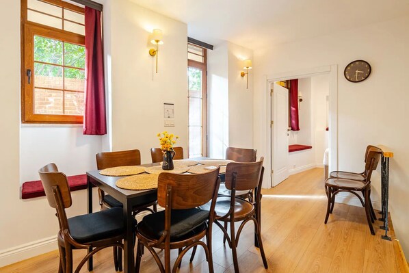 A dining area with a wooden table, chairs, and a vase of yellow flowers. - Villa with Private Garden, BBQ, Sauna and Turkish Bath in Balat (Istanbul)