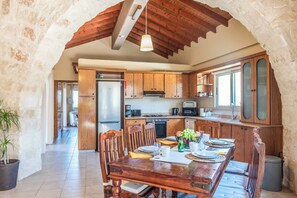 A kitchen with wooden cabinets, a dining table with chairs, and a refrigerator.
