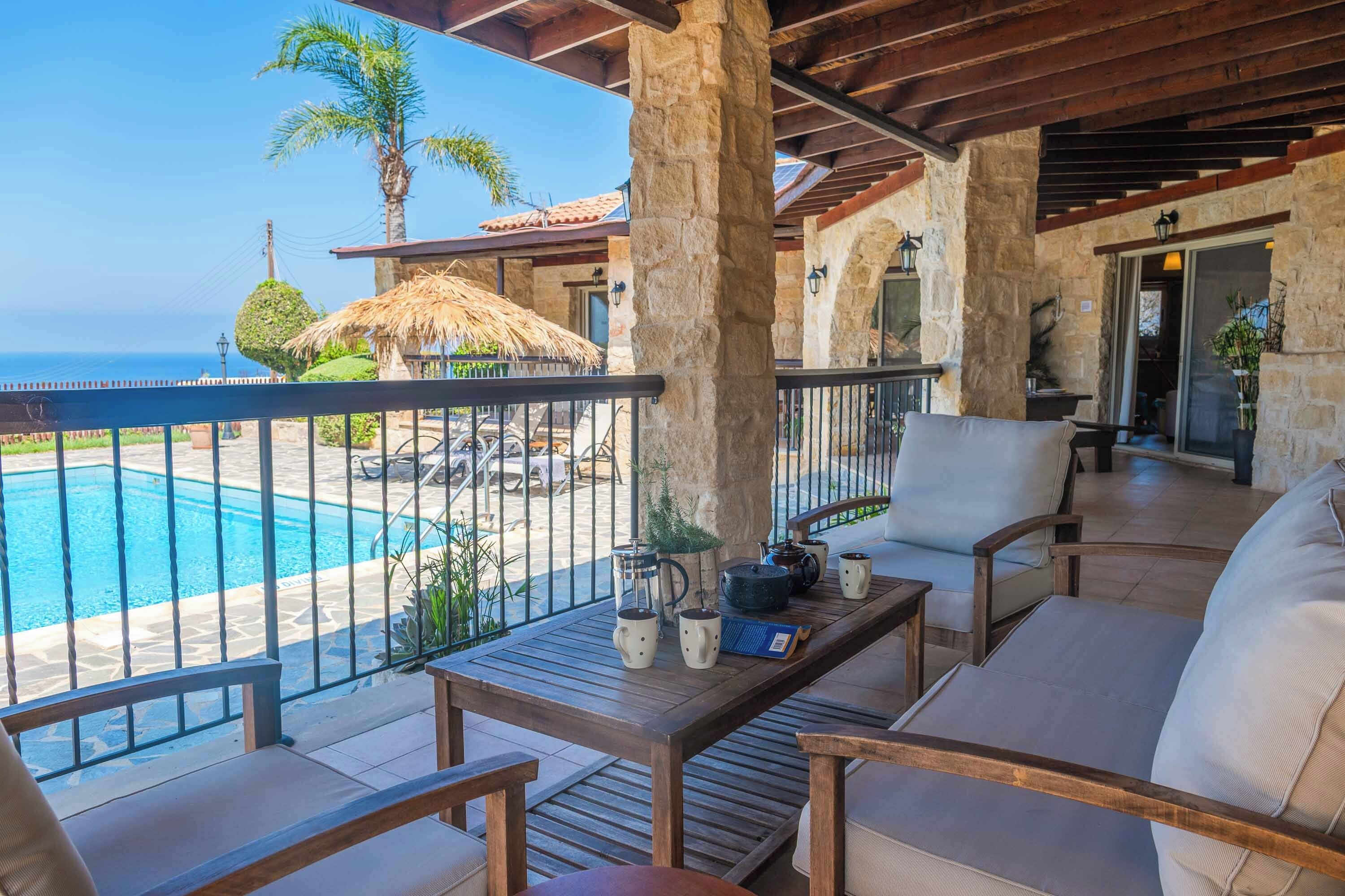A balcony with a pool view, stone pillars, and outdoor furniture.