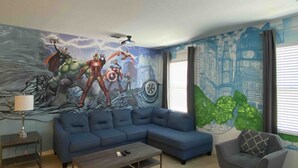 Un salón con un mural grande, un sofá modular, una mesa de centro, una mesita auxiliar y un sillón gris.