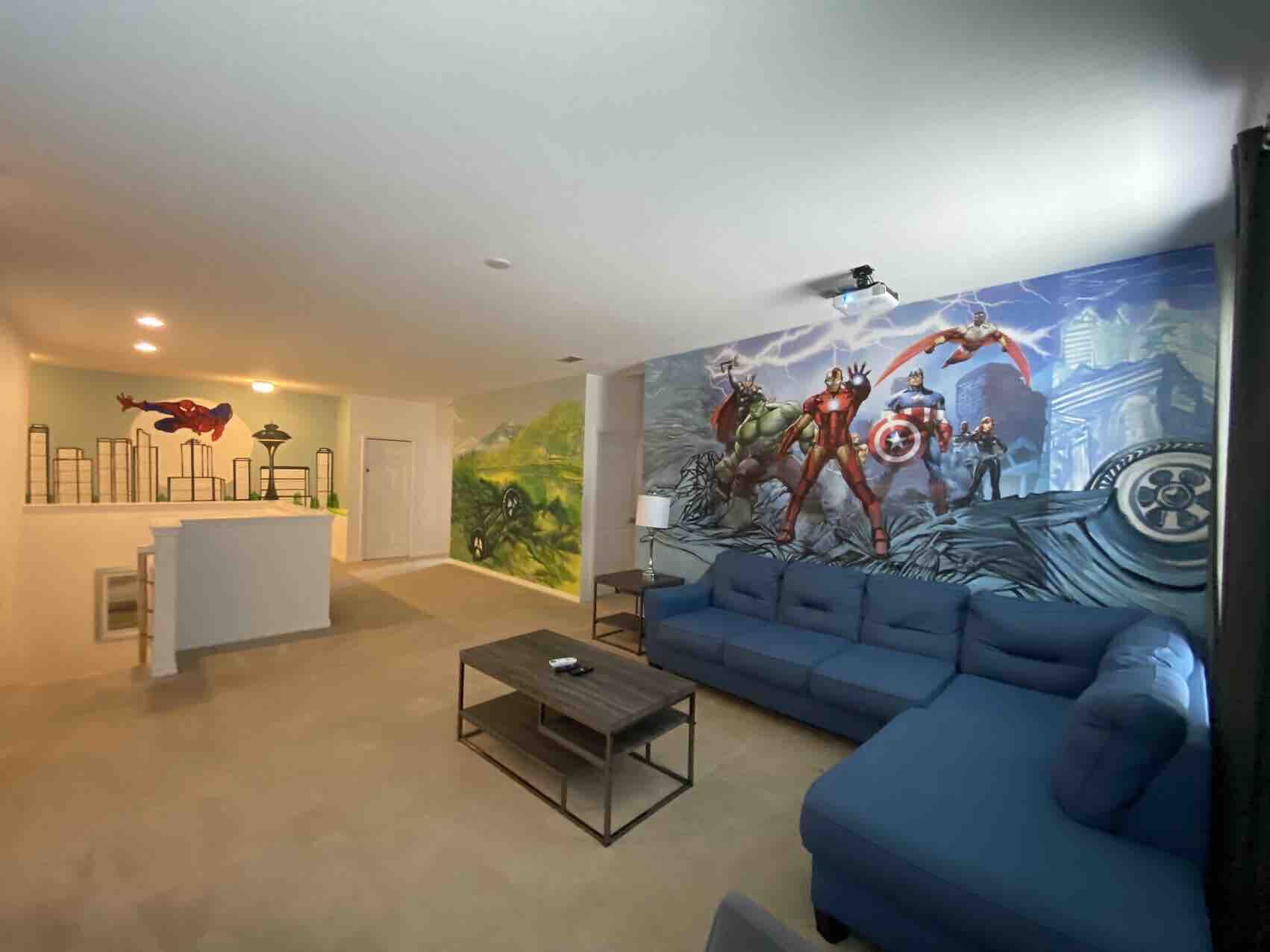 A modern living room with a blue sofa, a coffee table, a mural with superheroes, and a white reception desk.