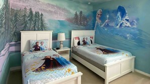 Un dormitorio con dos camas, un mural de paisaje invernal y una lámpara en el techo.
