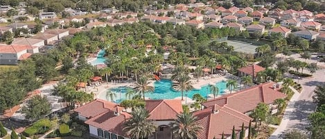 A residential area with a swimming pool, palm trees, and houses with red-tiled roofs.