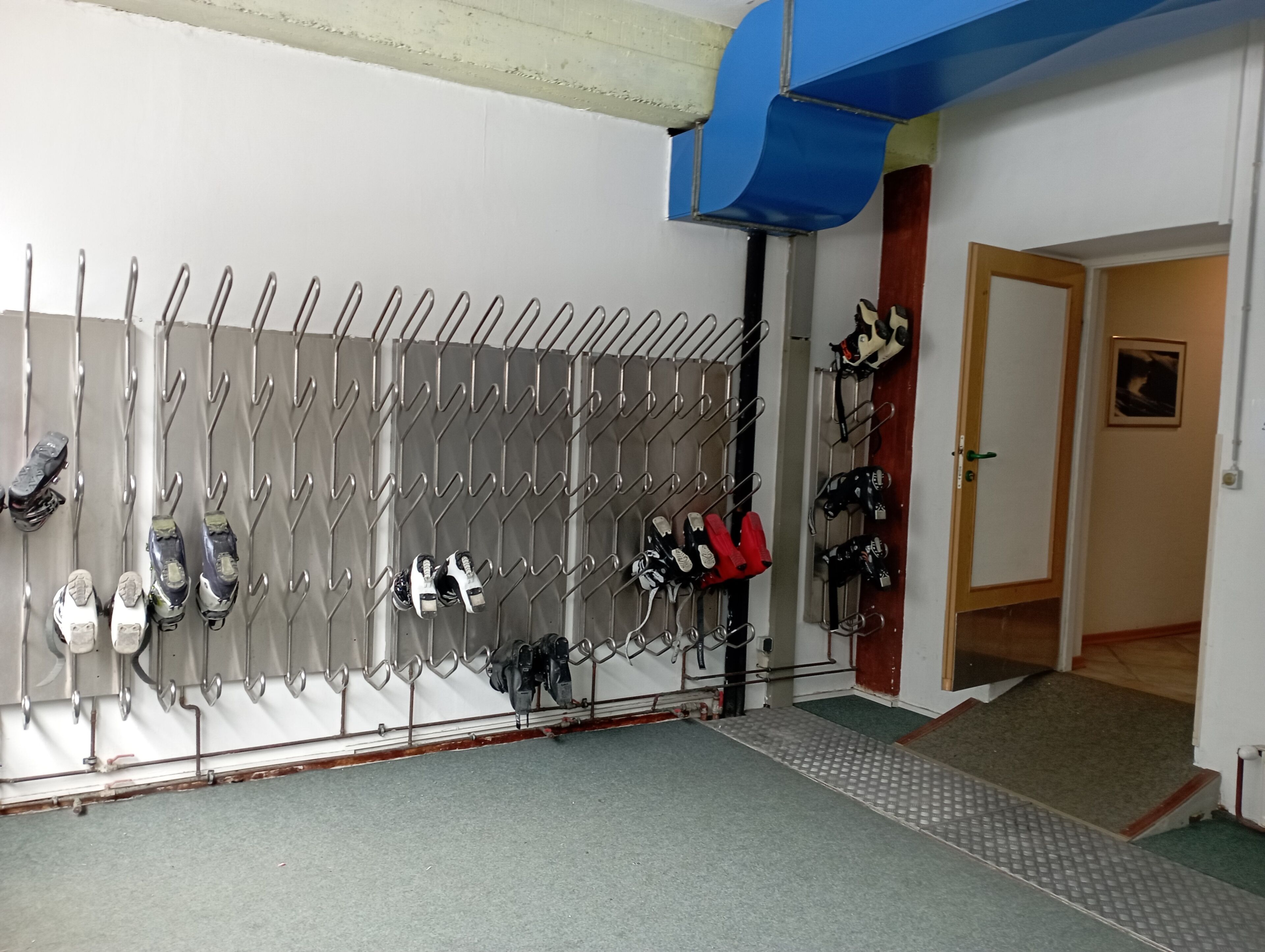 A room with a shoe rack holding various pairs of shoes.