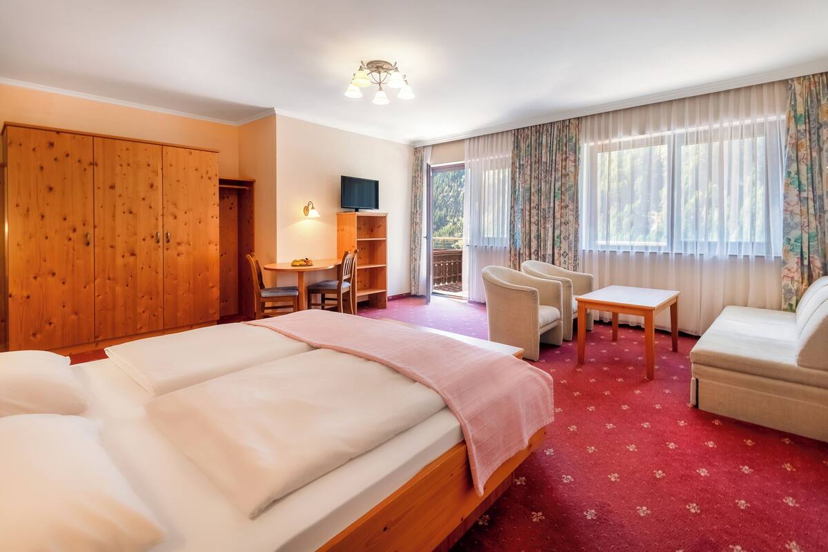 Habitación de hotel con una cama grande, un escritorio con una silla, un sofá y una televisión.
