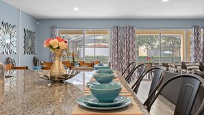 A dining area with a long table, blue bowls, and a vase with flowers. - Last Minute Disney! Private Pool, Hot Tub, Game Room & Themed Bedrooms. Book Now! #113675 (Orlando)
