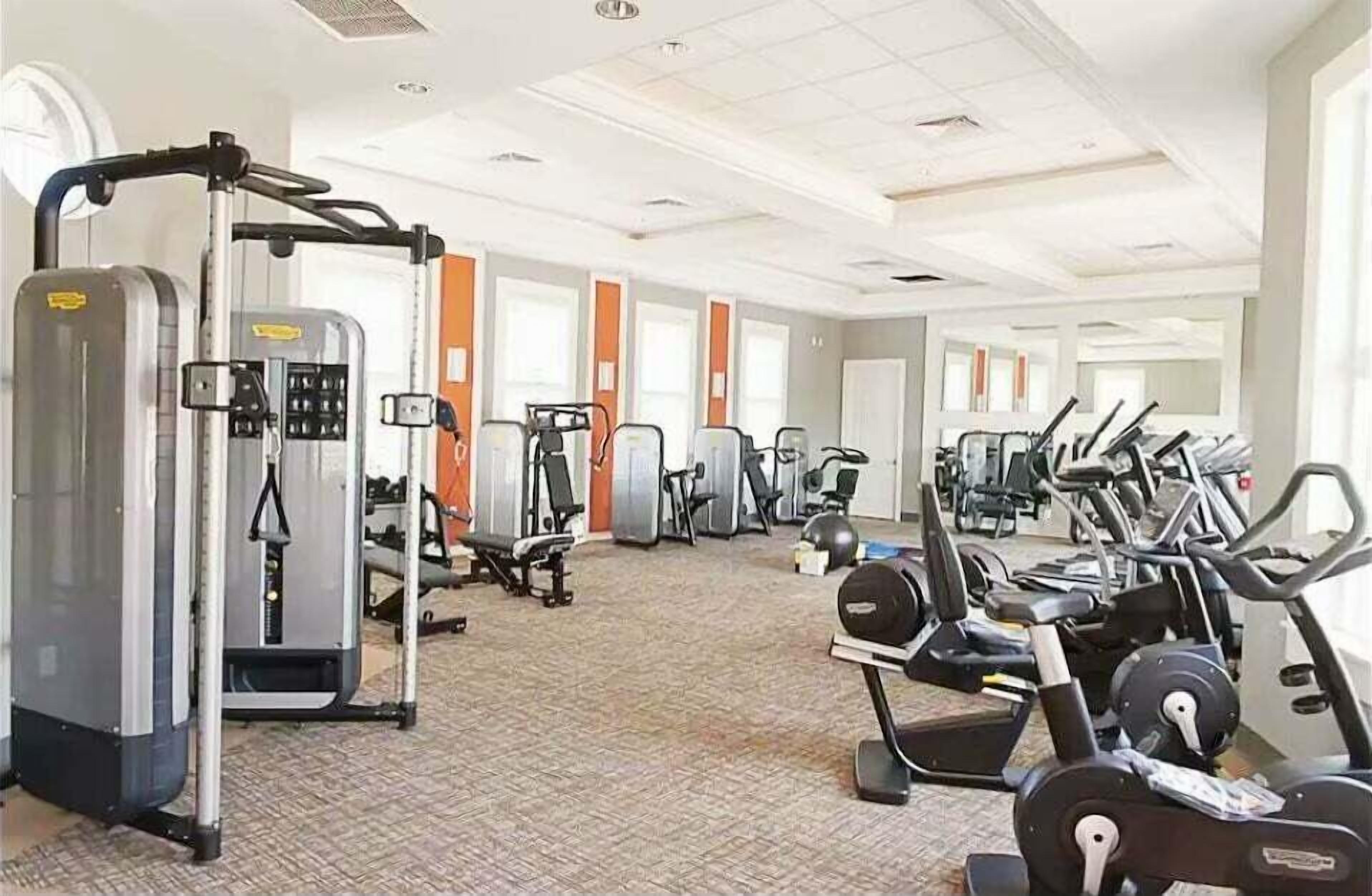 Une salle de sport équipée de divers appareils d’exercice, notamment des tapis de course et des appareils de musculation.